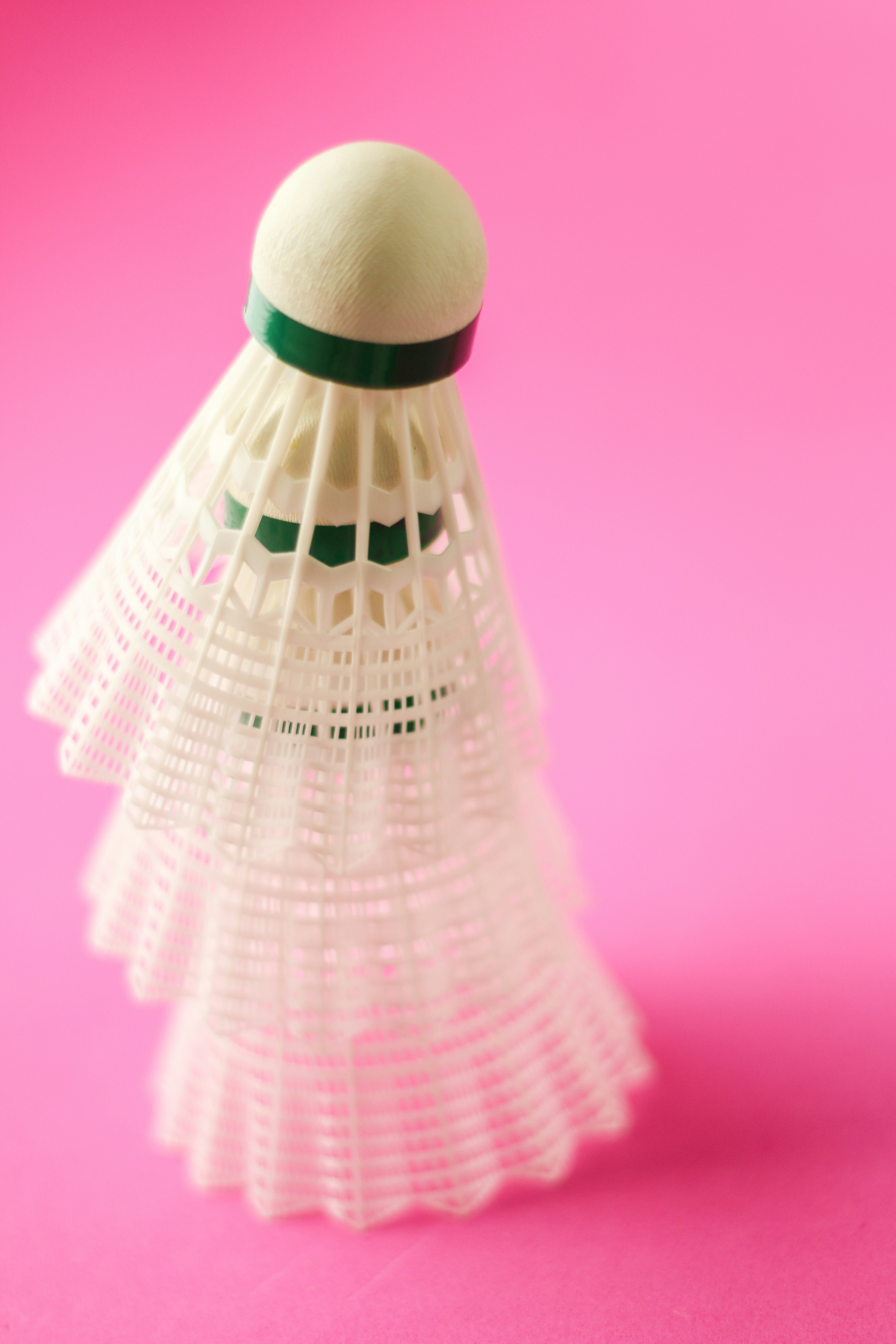 A white object with a green ribbon on a pink background