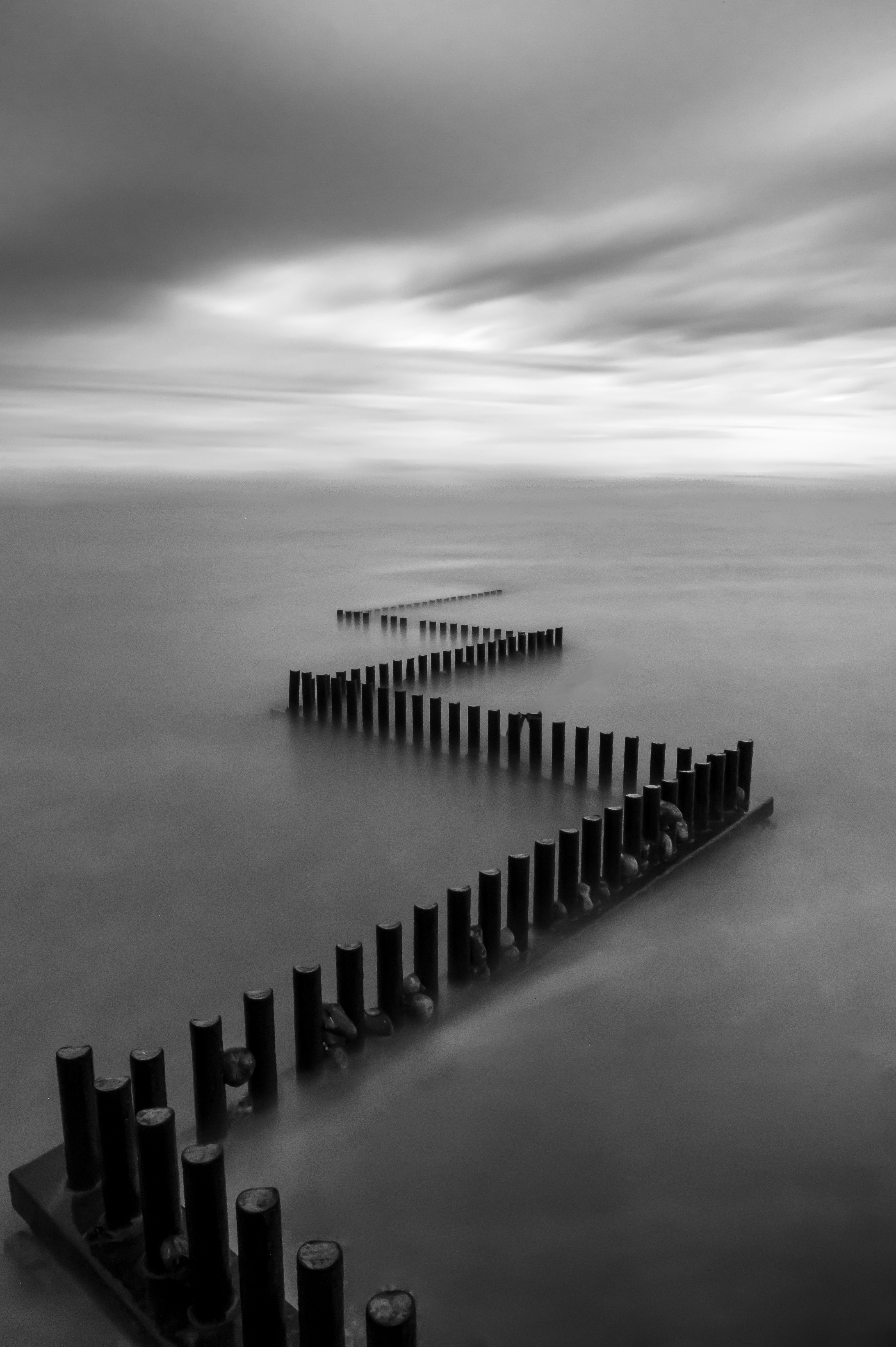 A black and white photo of a pier in the ocean