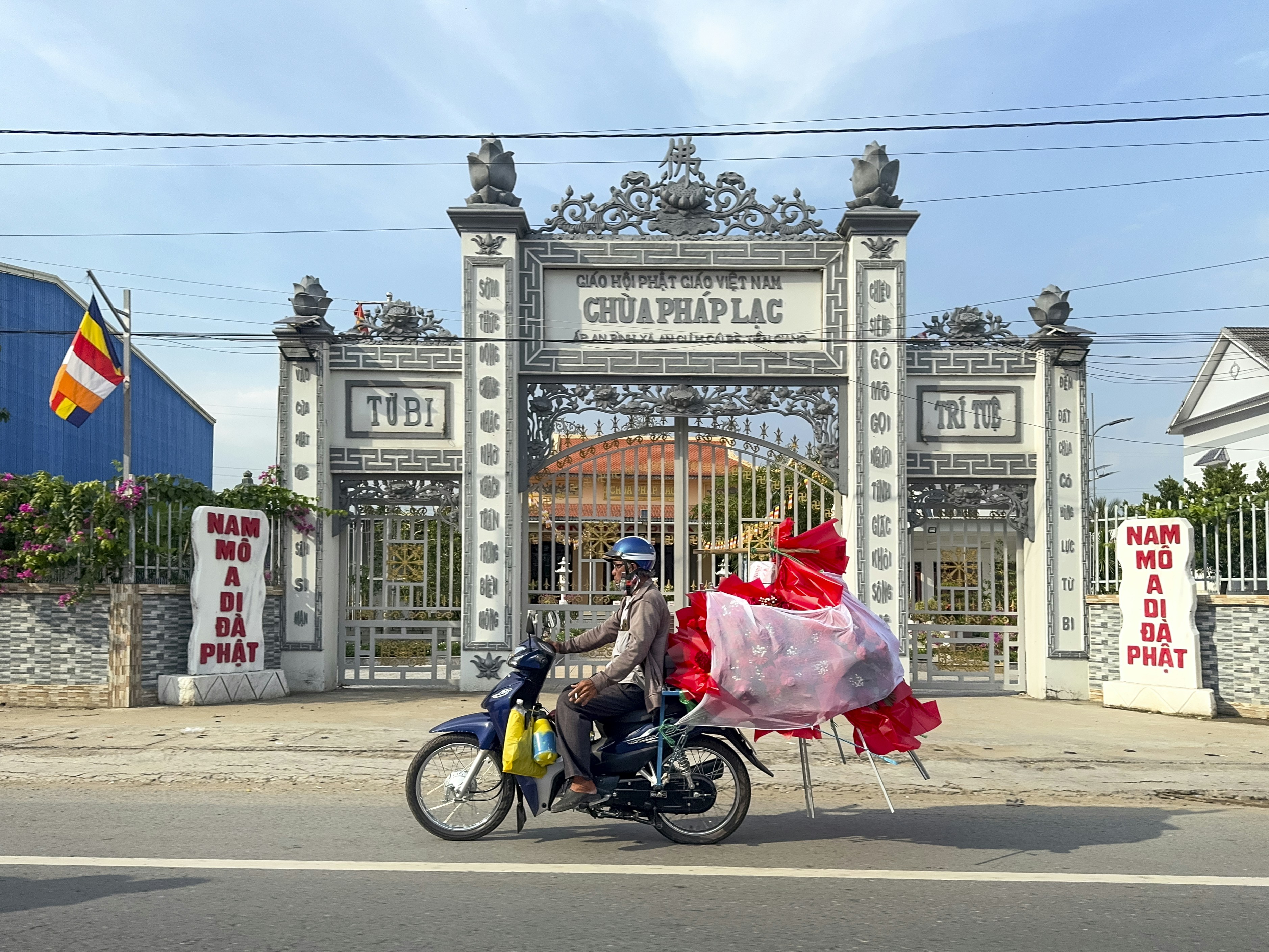 A man riding a motorcycle down a street past a gate