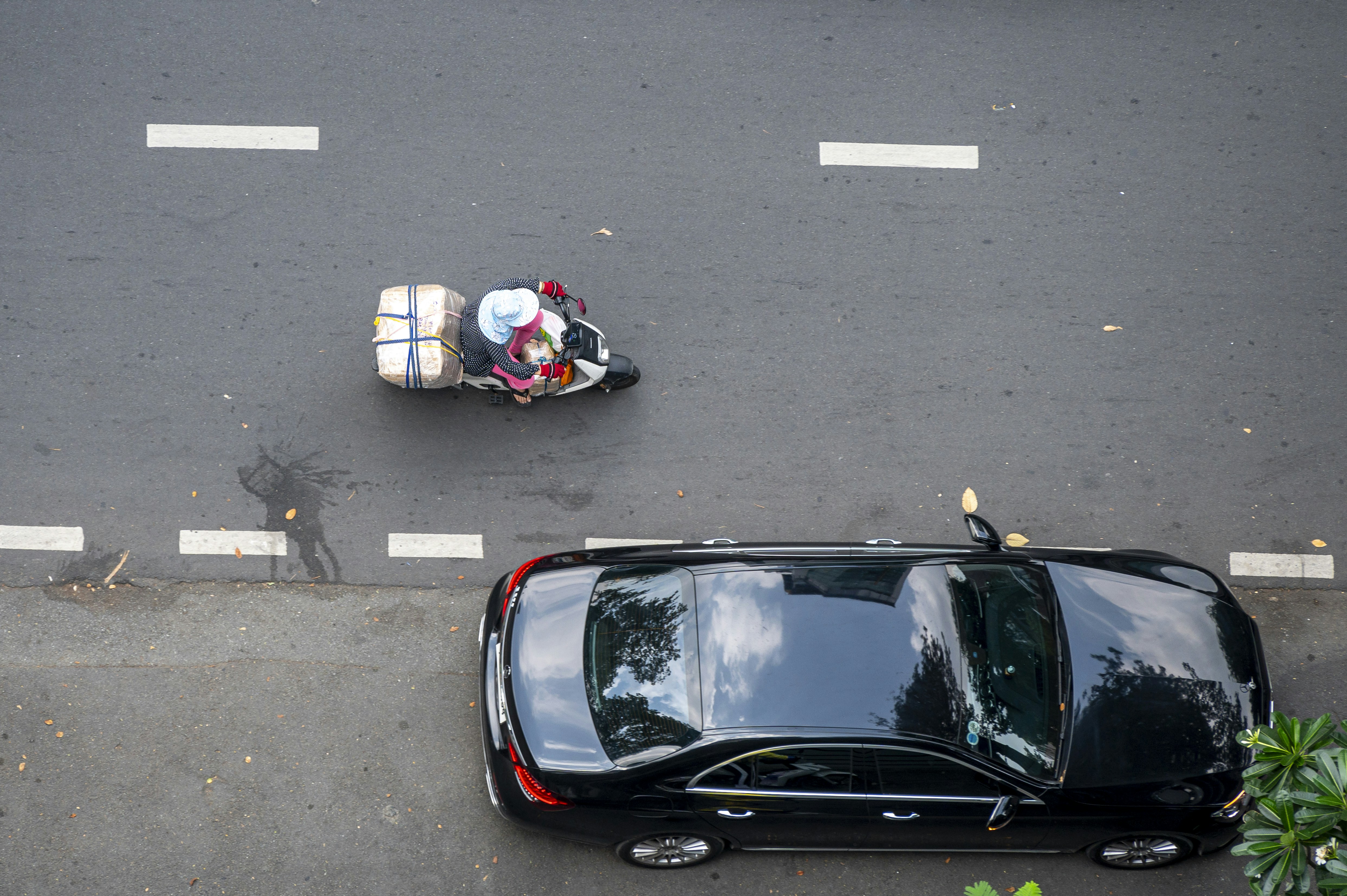 A black car driving down a street next to a motorcycle