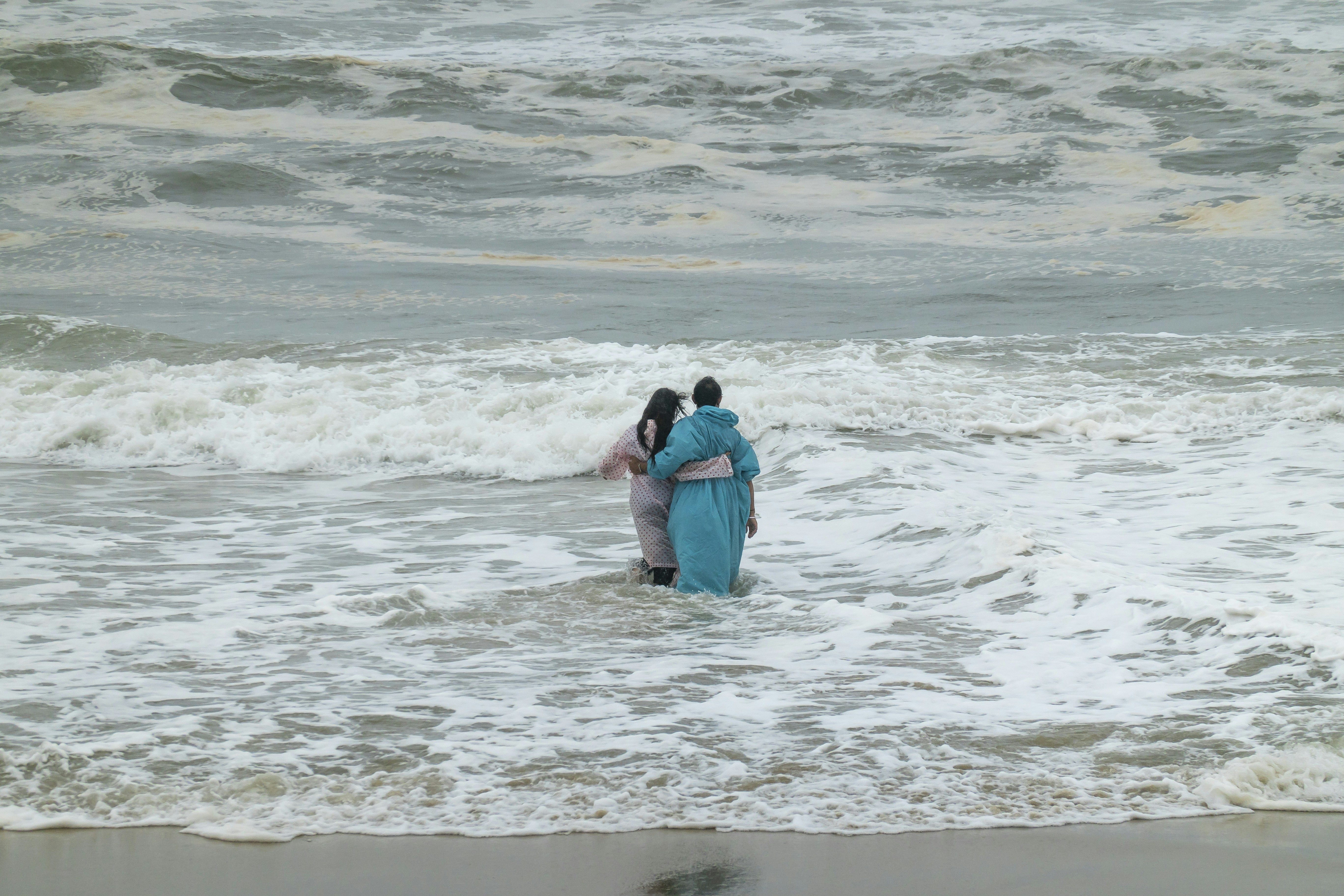 A couple of people standing in the ocean