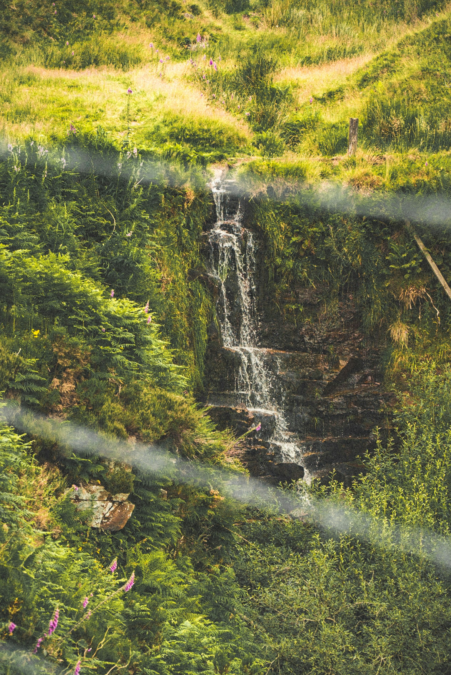A waterfall is seen through a wire fence