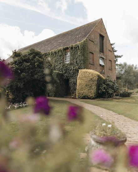 Ivy-clad brick barn conversion with a clipped hedge and lawn