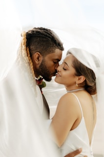 A bride and groom kissing under a veil
