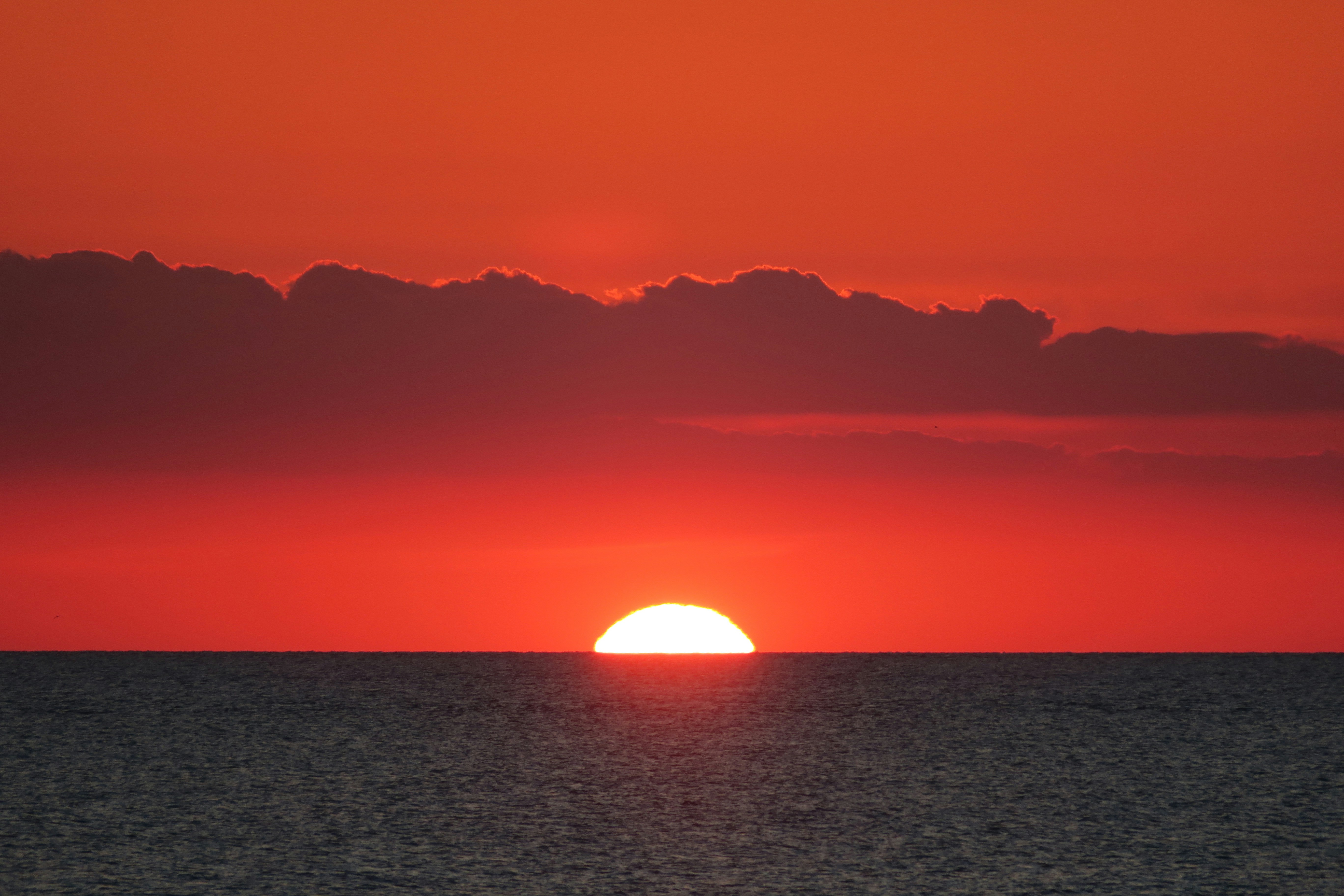 The sun is setting over the ocean on a cloudy day