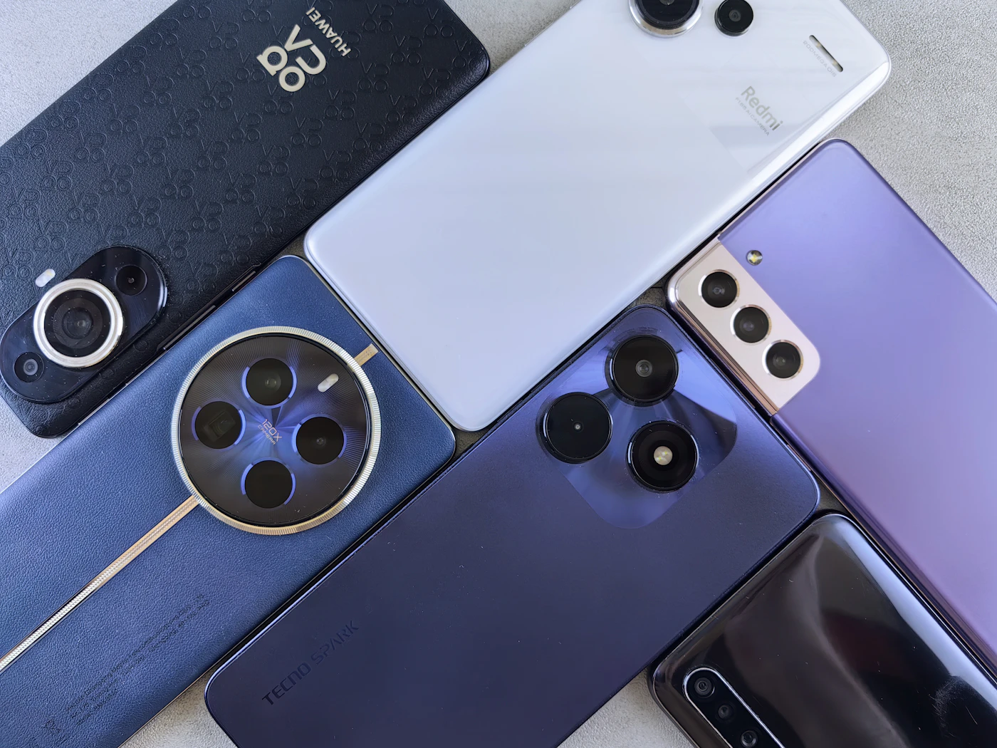 Several smartphones laid side by side, showing different clusters of two to four camera lenses on their backs