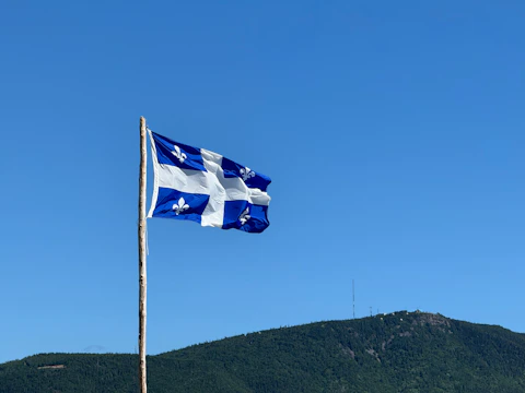 A flag flying in the wind with a mountain in the background