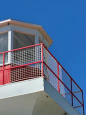 A red and white lighthouse with a blue sky in the background
