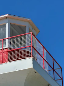 A red and white lighthouse with a blue sky in the background