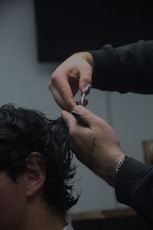 A man cutting another mans hair with a pair of scissors