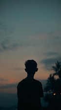 A silhouette of a person standing in front of a sunset