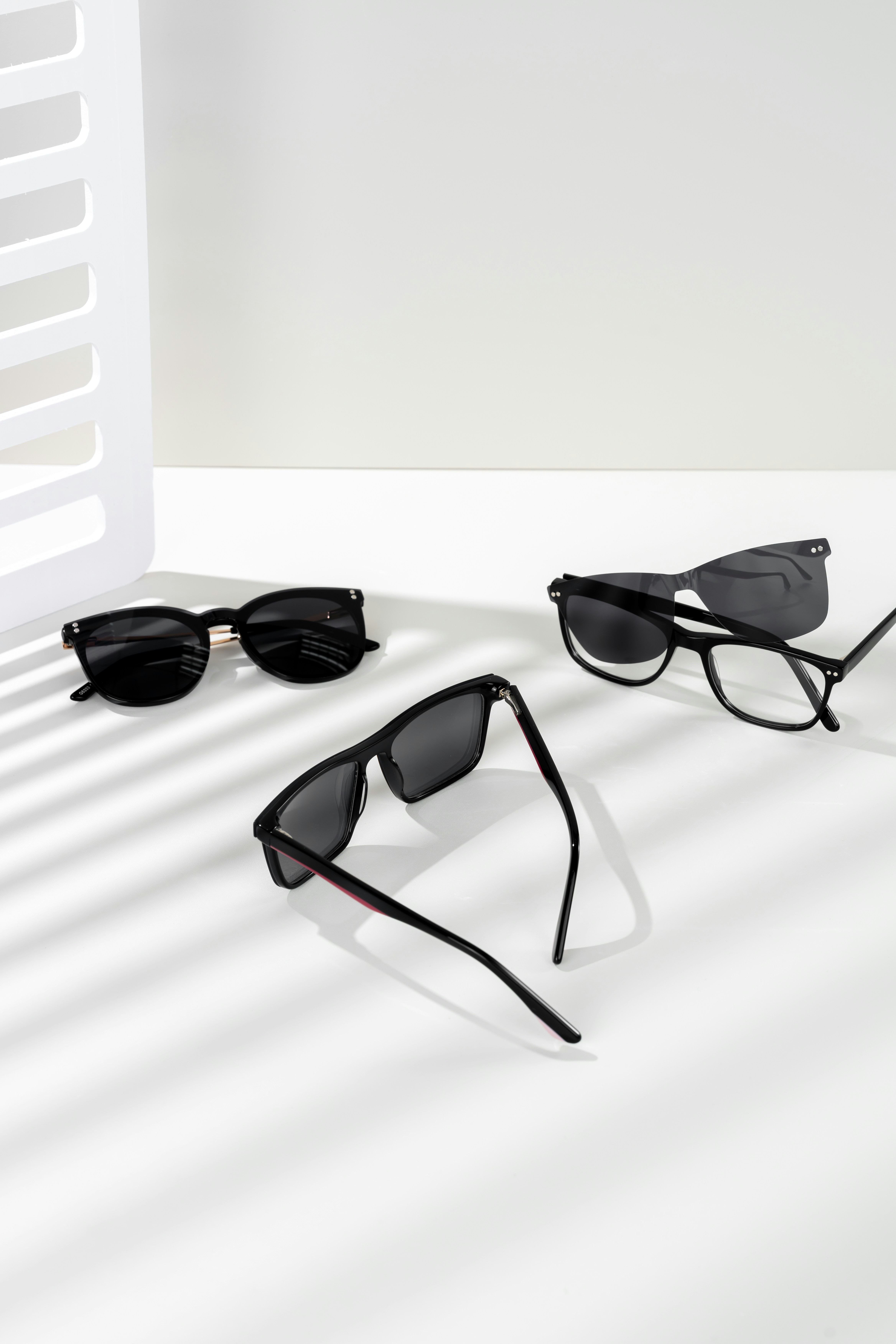 Three pairs of sunglasses sitting on top of a white surface