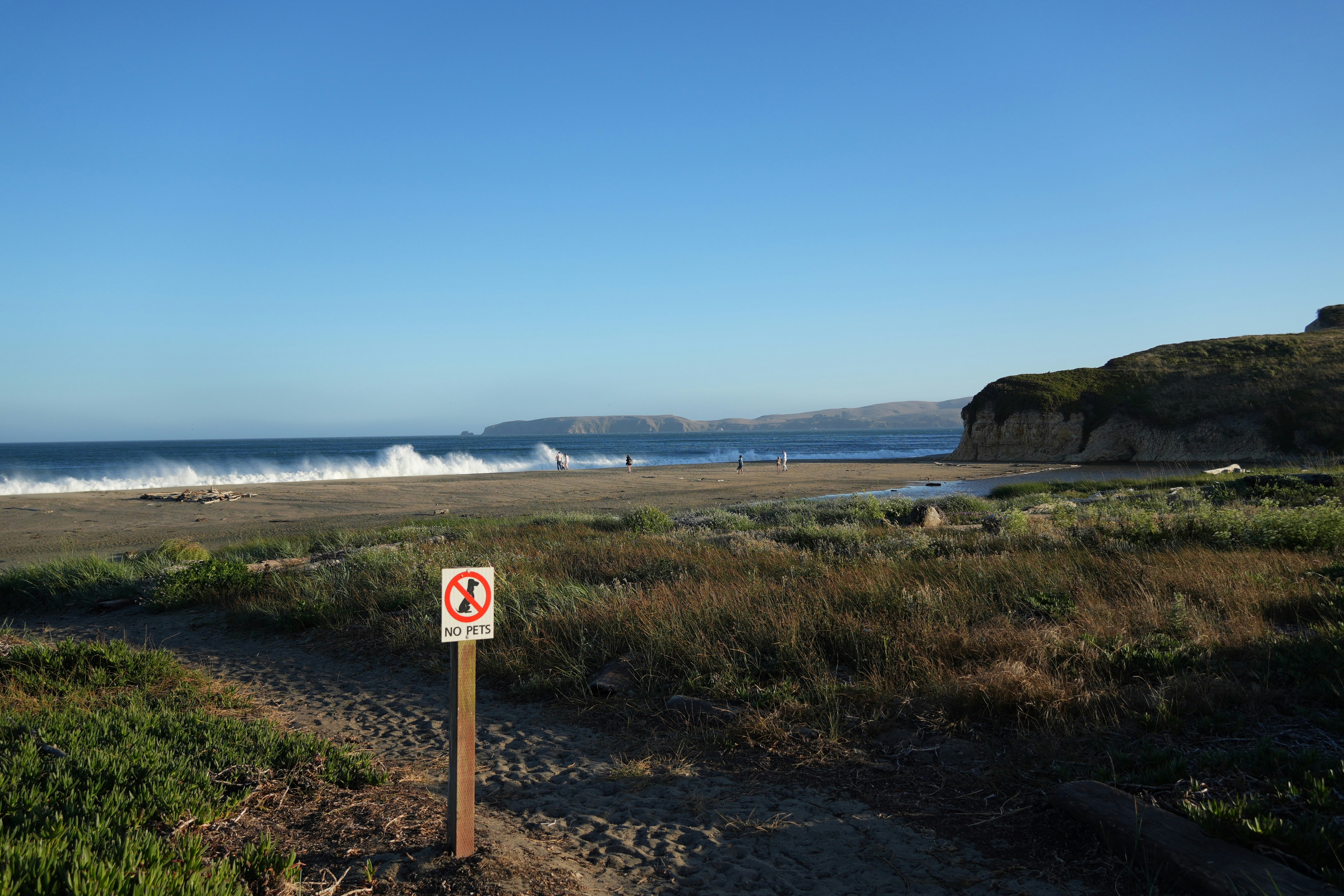 A sign on the side of a dirt road near the ocean