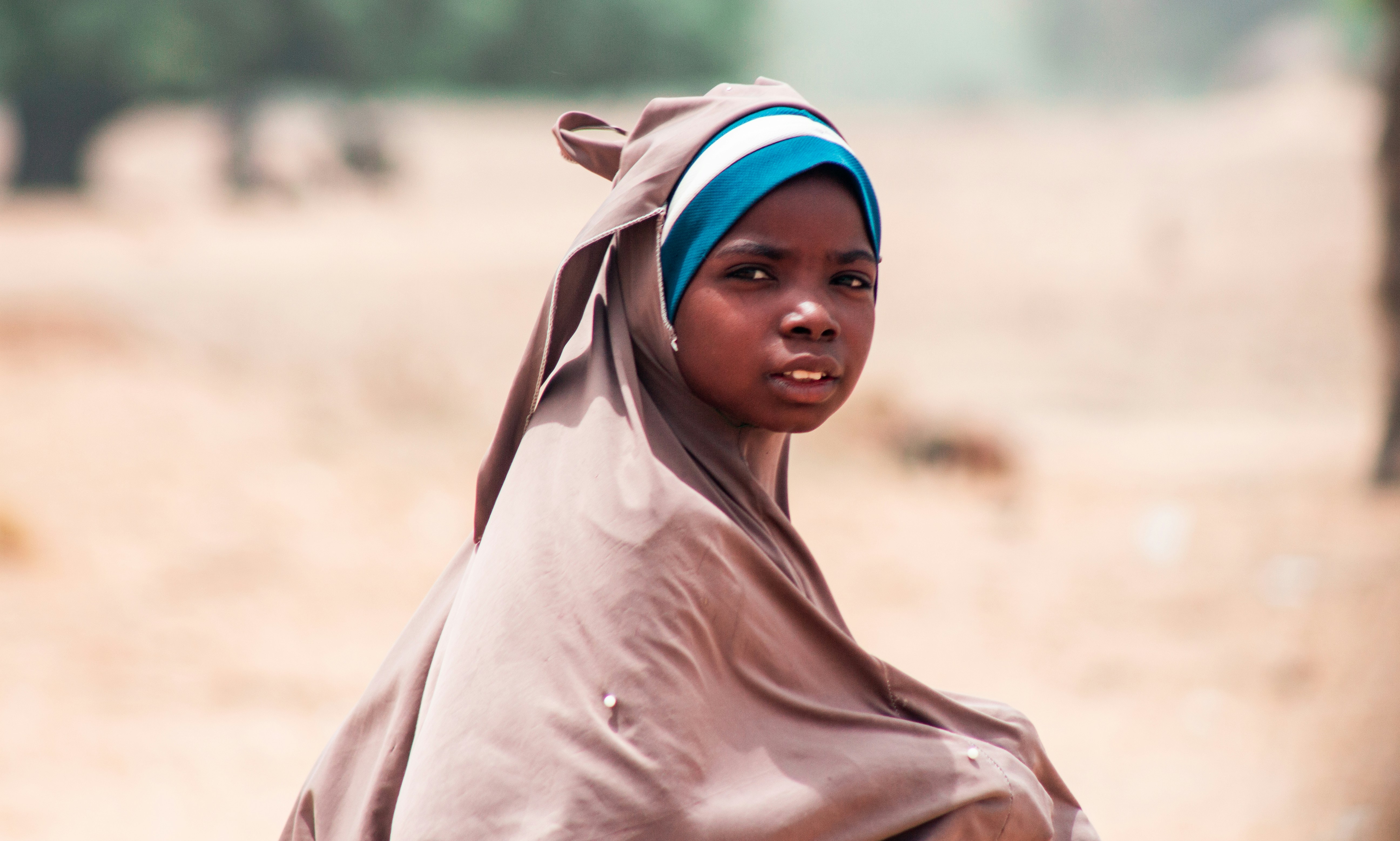 A woman in a brown shawl and a cow in the background