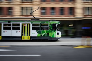A green and white trolley traveling down a street