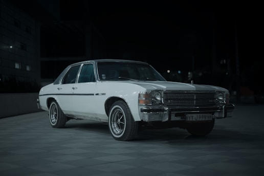A white car parked in a parking lot at night