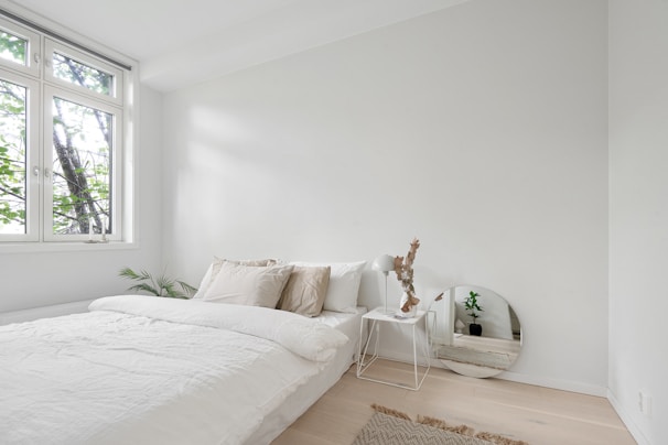 A bedroom with a white bed and a large window