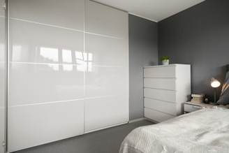 A bedroom with a white bed and a white closet