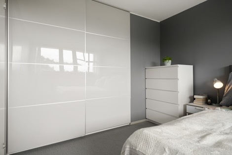 A bedroom with a white bed and a white closet