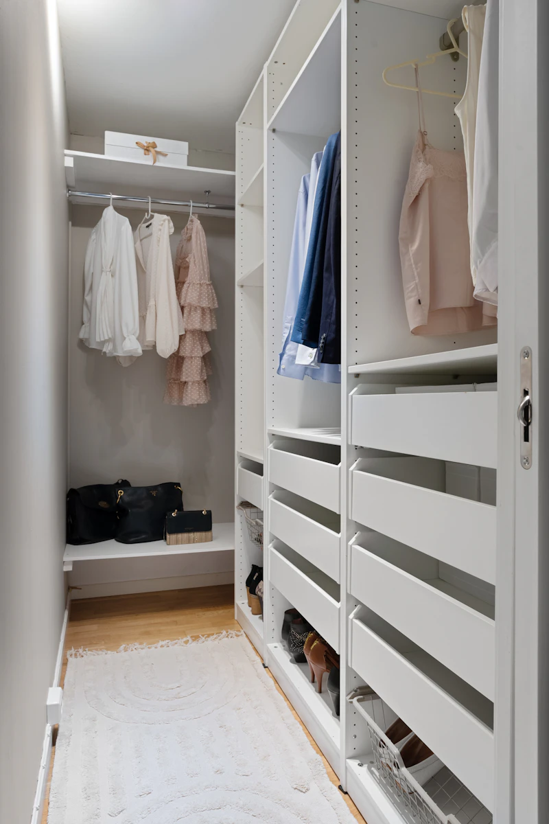 Modern walk-in closet with white shelving, drawers, and organized storage bins