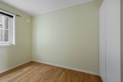 An empty room with a window and hard wood floor
