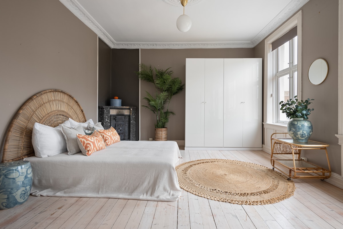 Scandinavian cozy bedroom with rattan headboard white wardrobe and plant