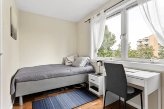 A bedroom with a bed, desk, and window
