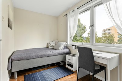A bedroom with a bed, desk, and window