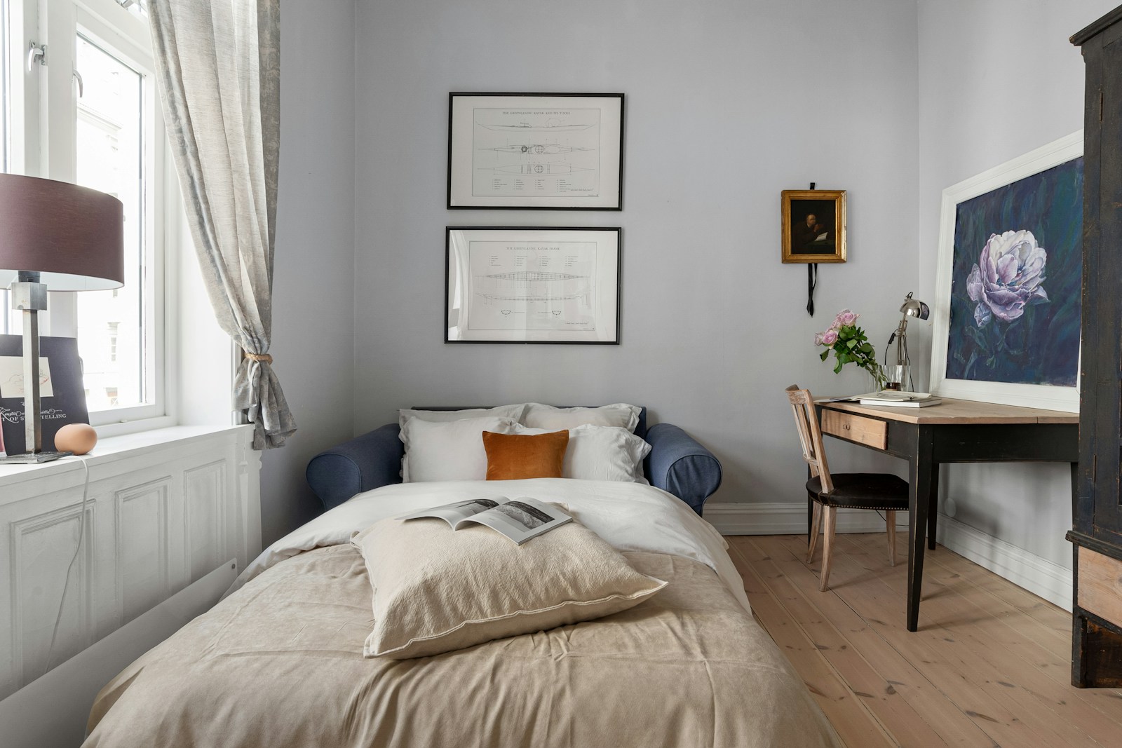 small studio apartment with bed used as sofa and built in desk under window