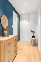 A blue and white hallway with a wooden dresser