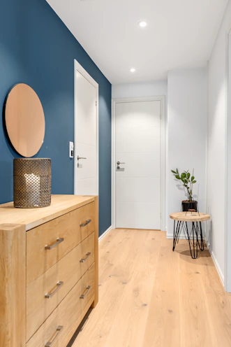 A blue and white hallway with a wooden dresser