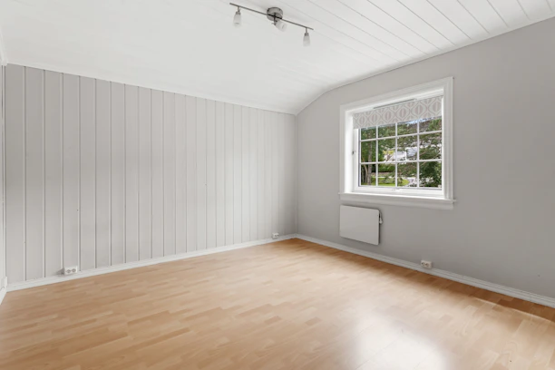An empty room with a wood floor and a radiator