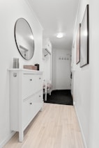 A white hallway with a white dresser and mirror