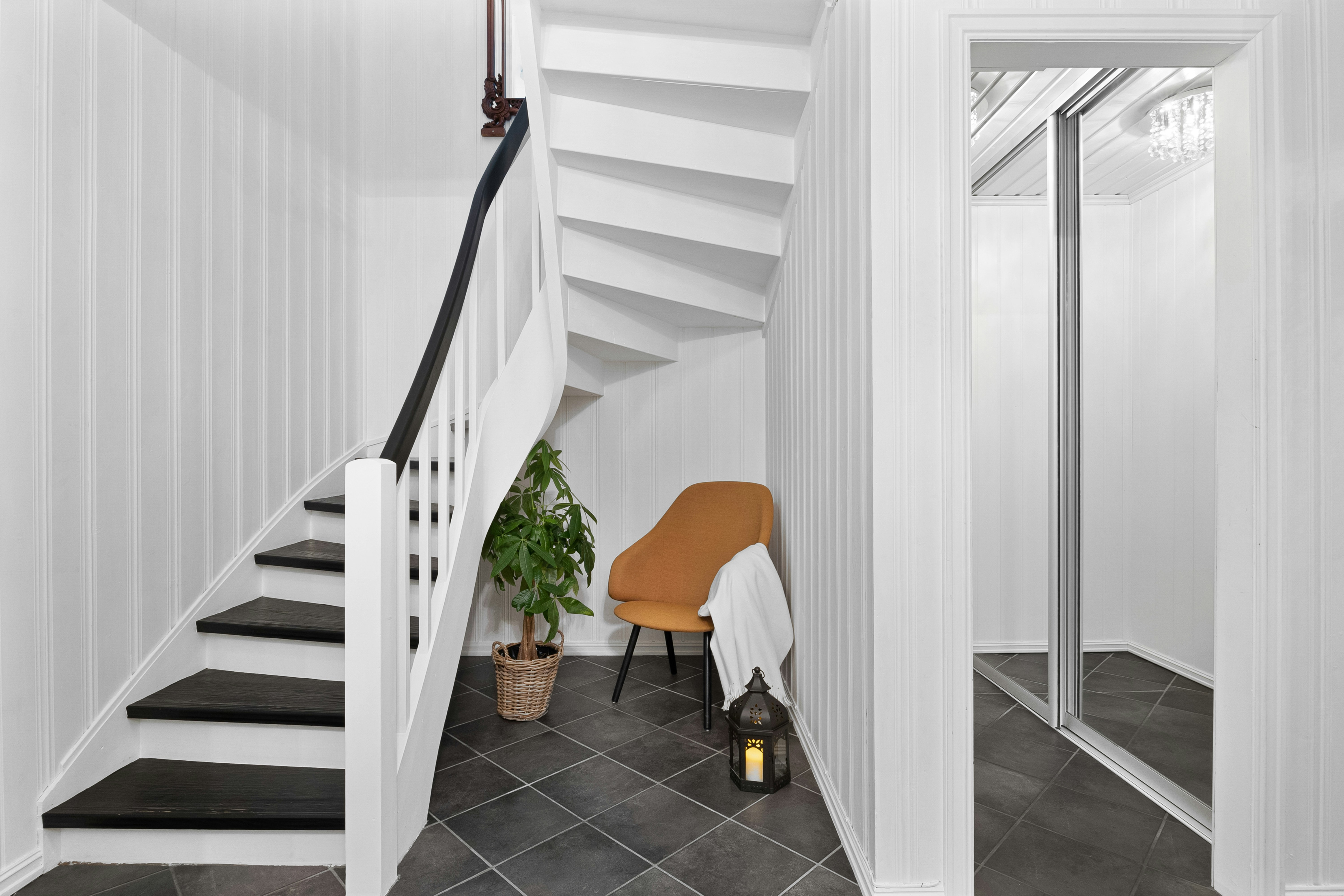 A white staircase with a chair and a potted plant
