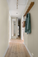 A long hallway with a coat rack and coat hanging on the wall