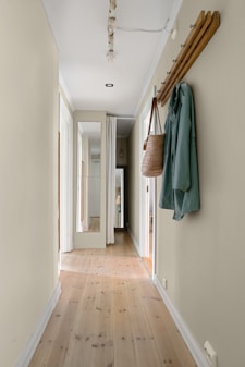 A long hallway with a coat rack and coat hanging on the wall