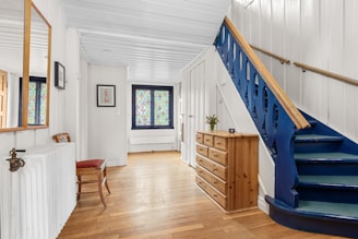 A blue staircase in a white house with wood floors