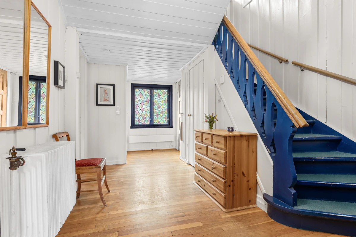 Entryway with a blue stair railing over wide-plank hardwood.