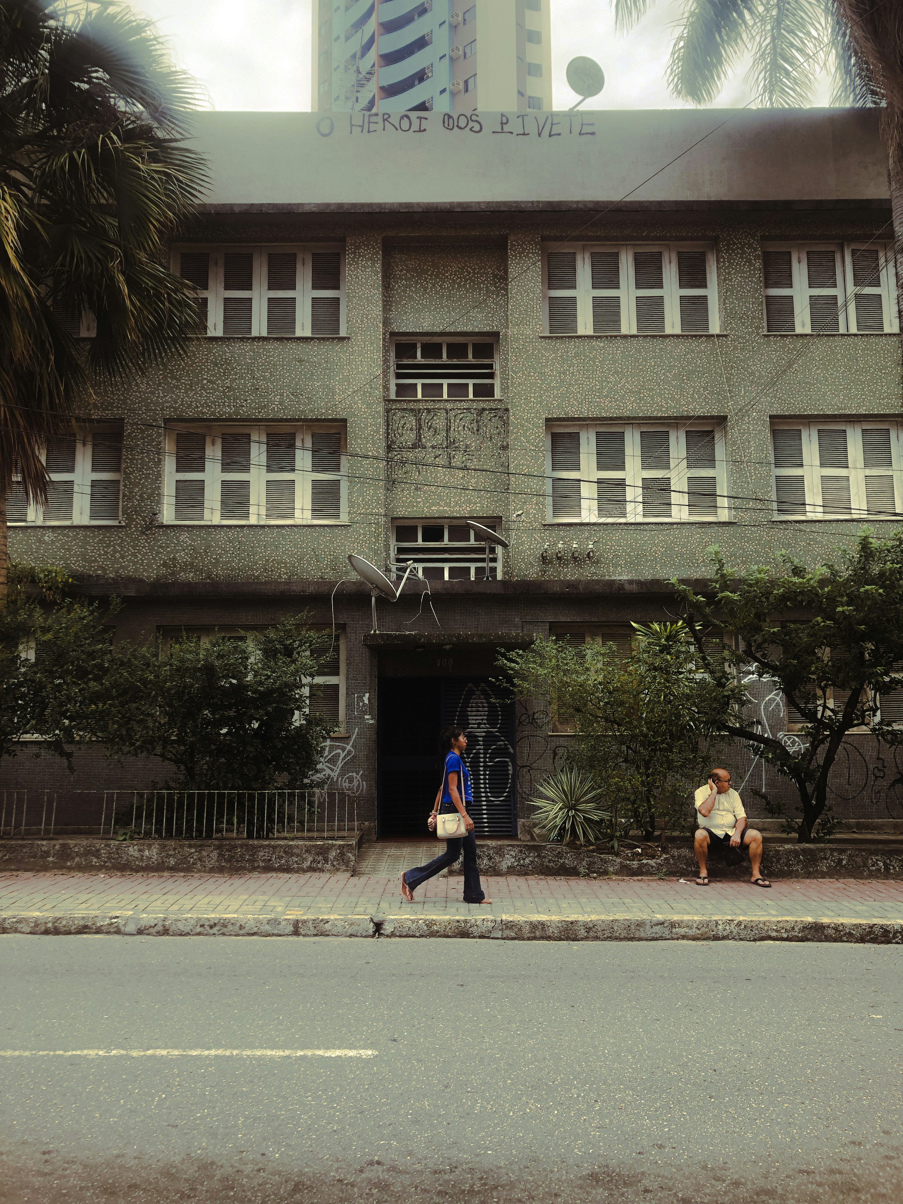A couple of people walking down a street next to a tall building