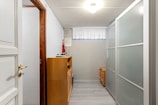 A narrow hallway with white walls and a wooden door