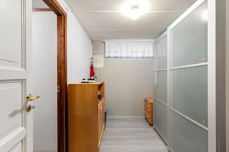 A narrow hallway with white walls and a wooden door