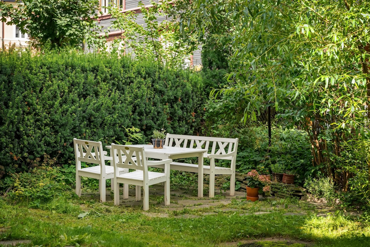 A white table and four chairs in a garden
