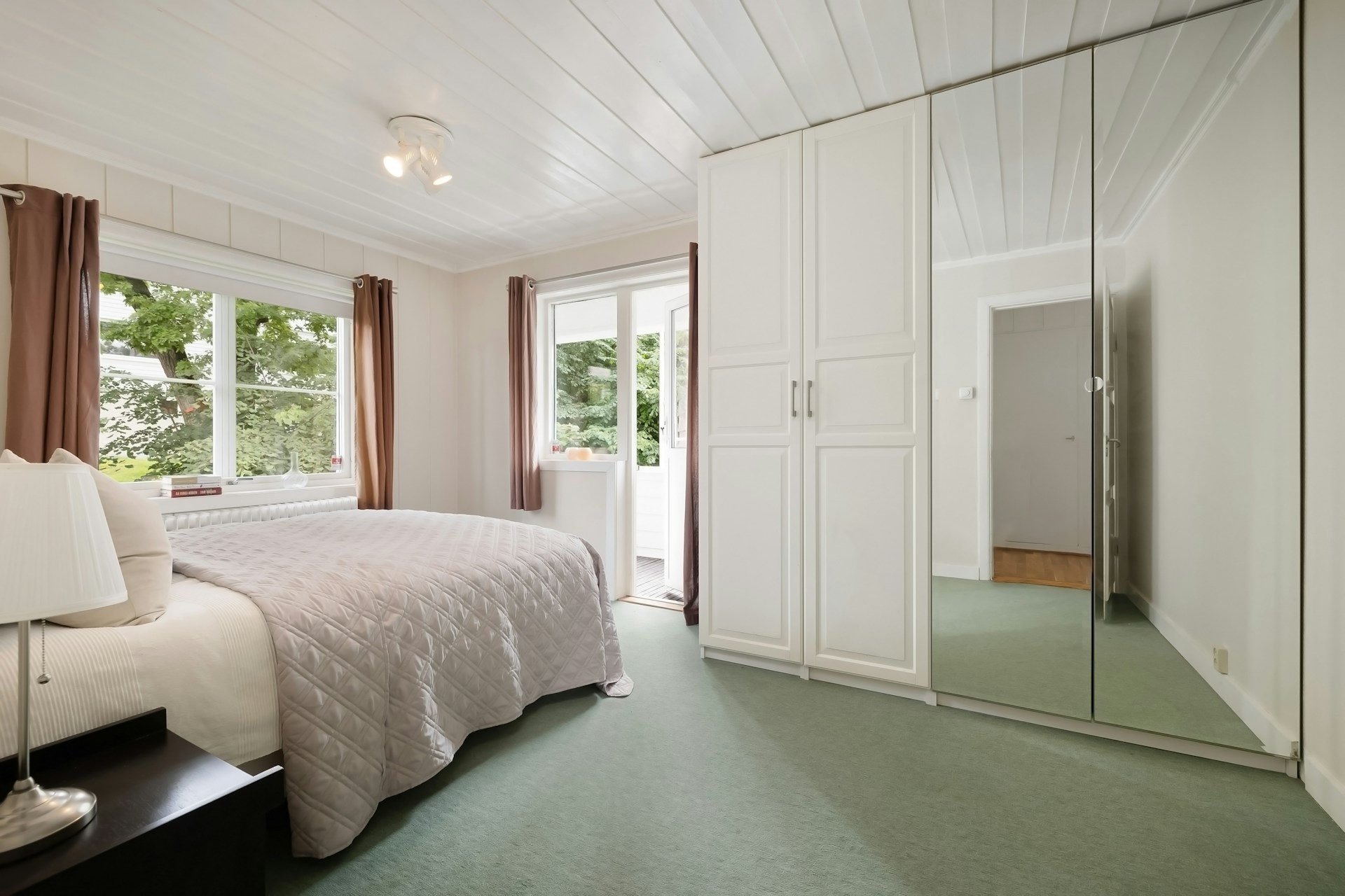 A bedroom with a large bed and a mirrored closet