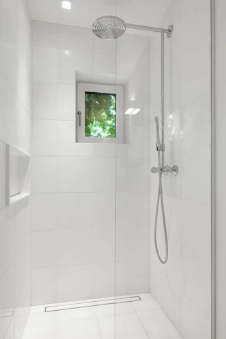 A bathroom with a walk in shower next to a window