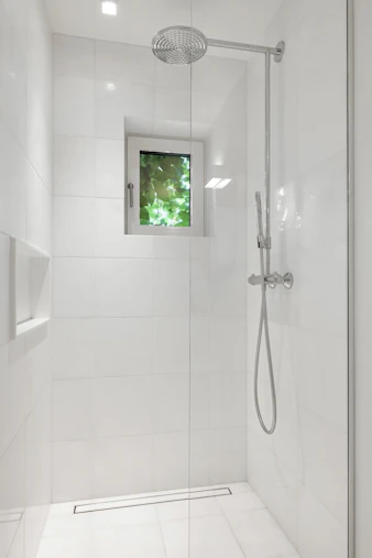 A bathroom with a walk in shower next to a window