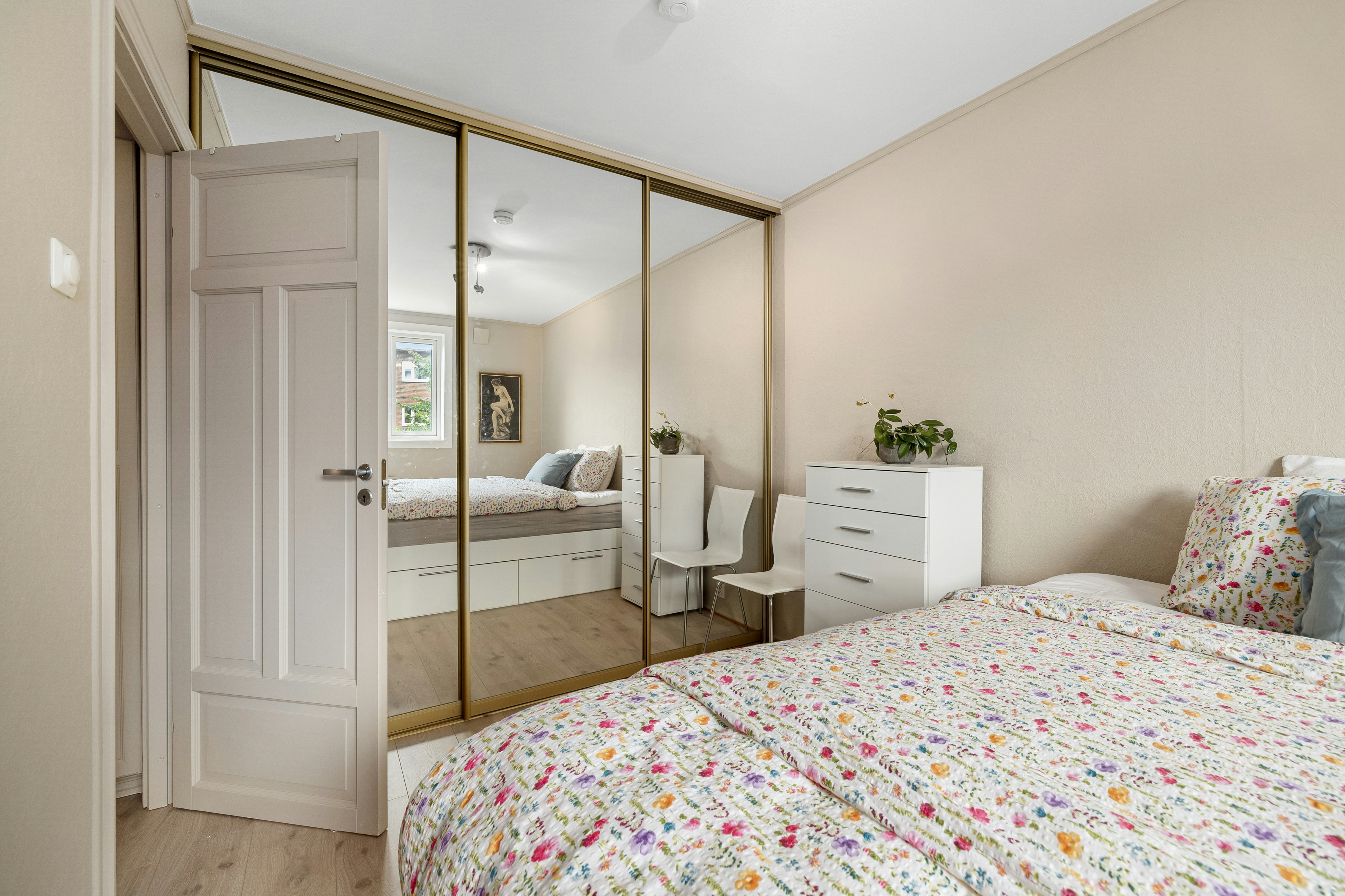 A bedroom with a bed, dresser and mirror