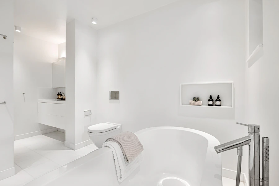 Une salle de bain blanche et claire avec une grande baignoire et un lavabo, lumière douce