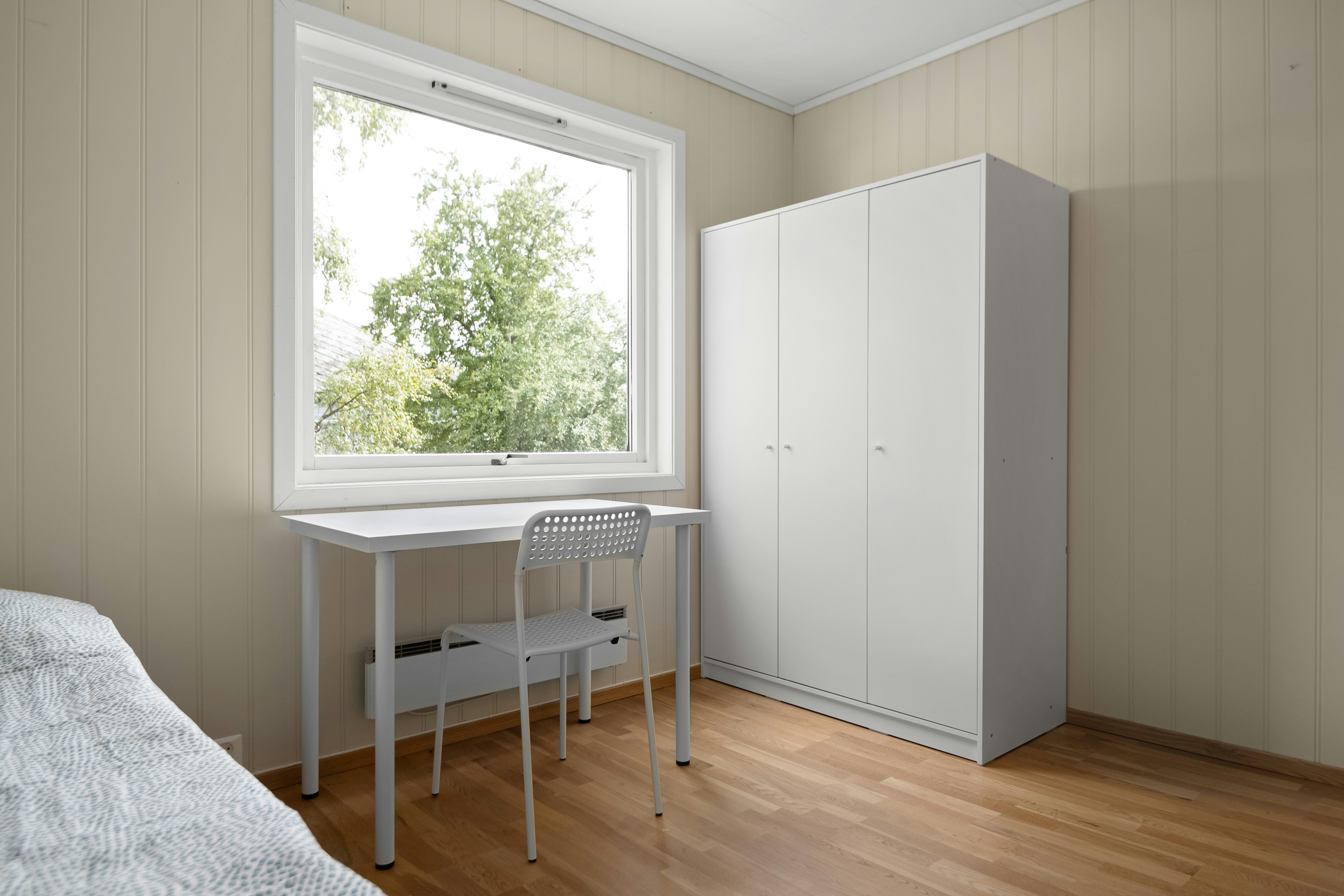 A bedroom with a bed, desk and a window