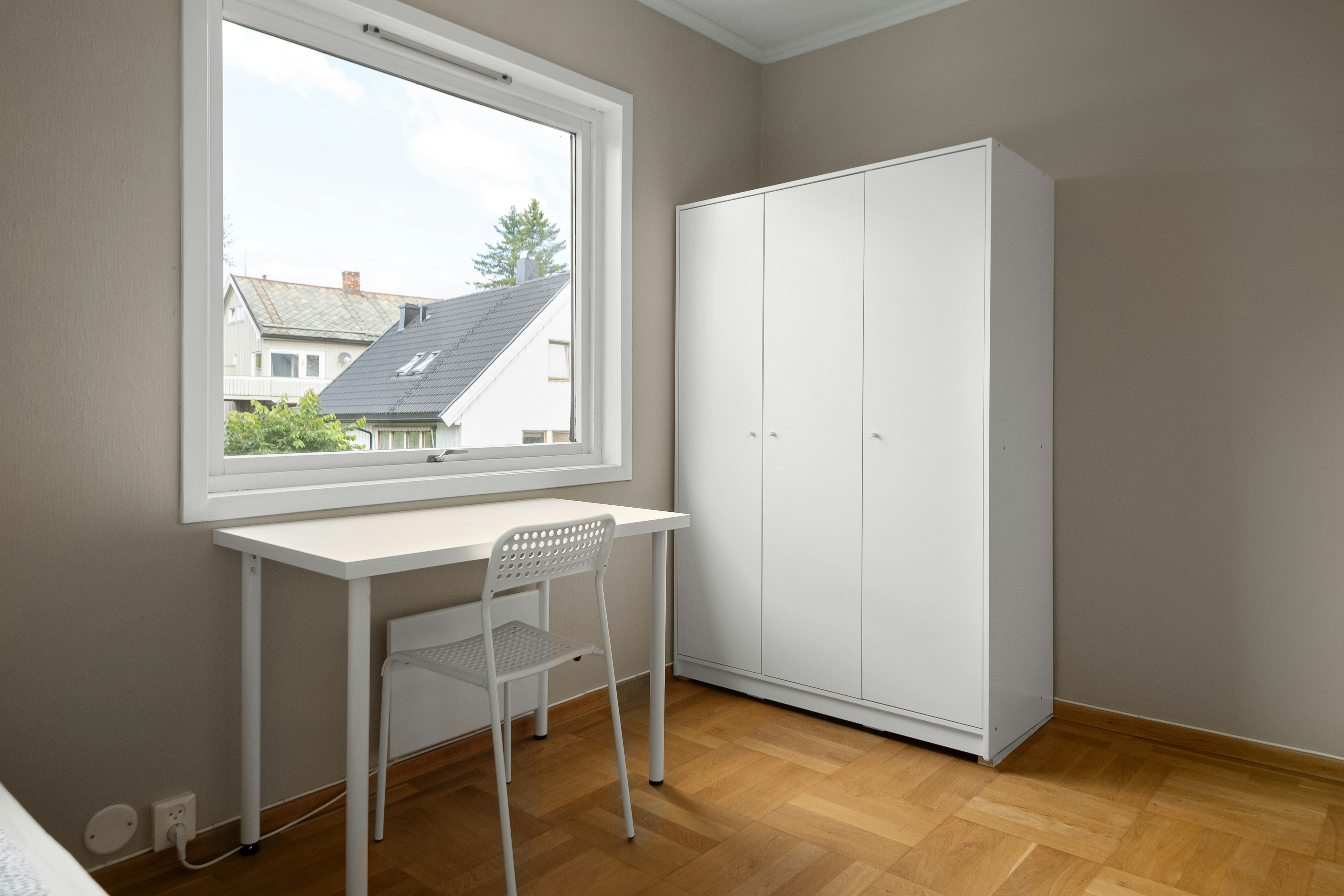 A bedroom with a desk and a window