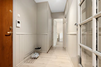 A hallway with a wooden door and a pair of shoes on the floor